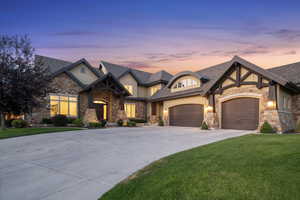 Craftsman-style house with a yard, concrete driveway, stone siding, a garage, and a shingled roof