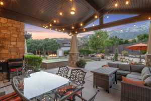 Patio terrace at dusk with outdoor lounge area, a patio, a fenced backyard, a storage shed, and a mountain view