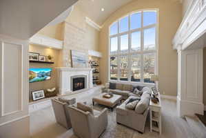 Carpeted living area featuring a high barrel ceiling and a large fireplace