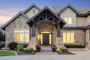 Exterior entry at dusk featuring stone siding and a standing seam roof