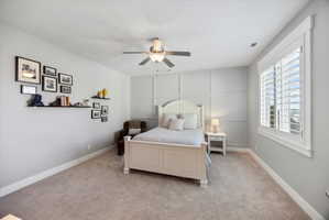 Carpeted bedroom with a ceiling fan and a decorative wall