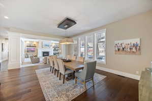 Dining area with dark wood-type flooring, a glass covered fireplace, and recessed lighting