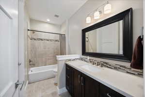 Bathroom featuring vanity, shower / bath combination with curtain, and backsplash