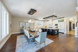 Dining space with dark wood-style floors, arched walkways, and recessed lighting