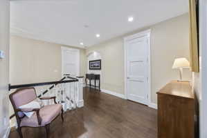 Sitting room with dark wood-type flooring, recessed lighting, an upstairs landing, and arched walkways