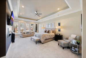 Carpeted bedroom with recessed lighting, ceiling fan, a raised ceiling, and crown molding