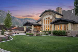 Back of property with stone siding, a patio, a chimney, a mountain view, and a shingled roof