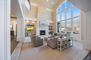 Living room with a fireplace, light colored carpet, crown molding, vaulted ceiling, and arched walkways