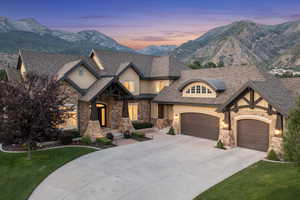 View of front of property featuring a lawn, a mountain view, concrete driveway, a garage, and roof with shingles