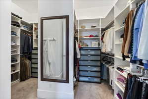 Walk in closet with light colored carpet