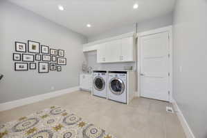 Laundry area featuring cabinet space, recessed lighting, washing machine and dryer, and light tile patterned flooring