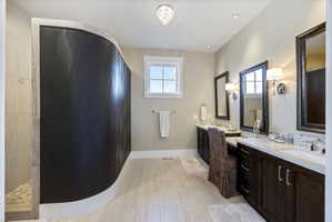 Bathroom with vanity, walk in shower, and light wood finished floors