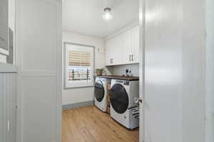 Laundry room with light wood finished floors, cabinet space, and independent washer and dryer