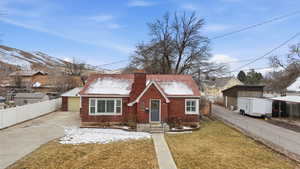 View of front of property with brick siding, a chimney, and driveway