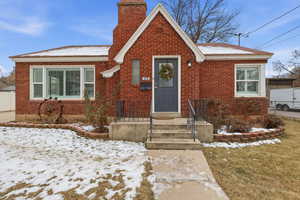 View of front of property featuring brick siding and a chimney