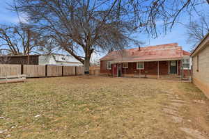Rear view of house featuring brick siding, a fenced backyard, and a patio