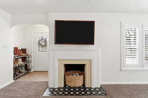 Detailed view of carpet floors, a tiled fireplace, arched walkways, and a textured ceiling