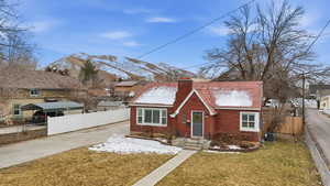 Tudor house with brick siding, a chimney, and driveway