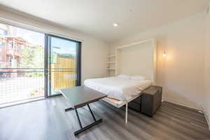 Bedroom with dark wood-style floors, access to exterior, and recessed lighting