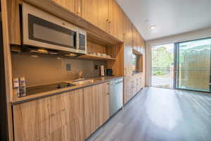 Kitchen featuring open shelves, stainless steel appliances, recessed lighting, light wood finished floors, and modern cabinets