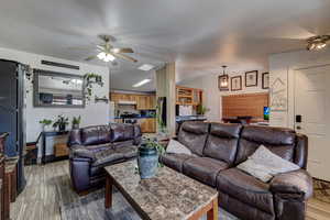 Living room with light wood-type flooring, a ceiling fan, and lofted ceiling