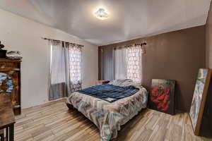 Bedroom with a textured wall, wood tiled floors, and a textured ceiling