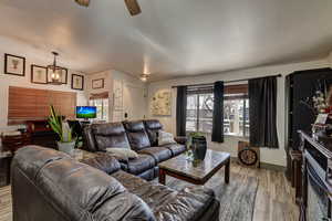 Living area featuring ceiling fan, a textured ceiling, and light wood-style flooring