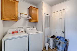 Laundry room with a heating unit, washing machine and dryer, crown molding, cabinet space, and light wood-style floors