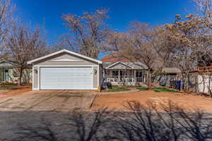 Ranch-style home with concrete driveway, covered porch, and an attached garage