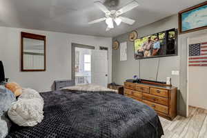 Bedroom with a ceiling fan, a textured ceiling, and ensuite bath