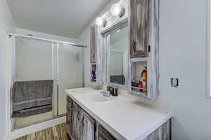 Bathroom featuring vanity, a stall shower, and light wood-style floors
