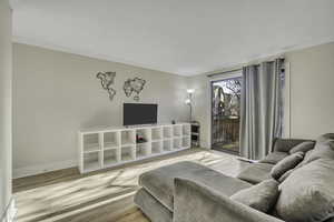 Living room with wood finished floors and ornamental molding