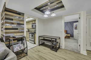 Kitchen featuring stainless steel appliances, light wood-type flooring, hanging light fixtures, a tray ceiling, and light countertops
