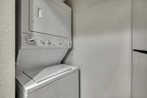 Laundry area with a textured wall and stacked washer and dryer