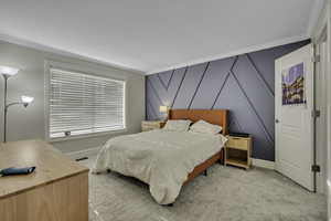 Bedroom with carpet, crown molding, a decorative wall, and an accent wall