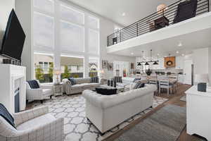 Living area with a high ceiling, recessed lighting, wood finished floors, and a fireplace