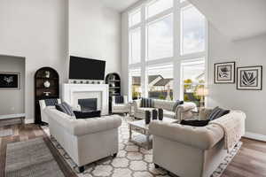 Living area with wood finished floors, a high ceiling, built in shelves, and a fireplace