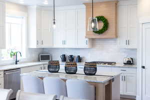 Kitchen featuring white cabinetry, light stone countertops, and a kitchen bar
