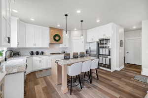 Kitchen featuring light stone countertops, a center island, a kitchen breakfast bar, and dark wood-style flooring