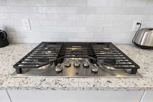 Kitchen view of stainless steel gas stovetop and light stone countertops