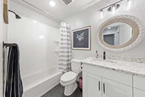 Full bathroom with vanity, shower / tub combo, dark tile patterned floors, and recessed lighting