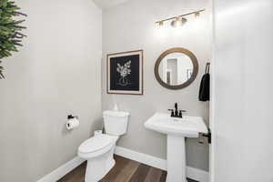 Half bathroom with toilet and dark wood-type flooring