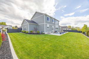 Back of property with board and batten siding, a fenced backyard, a patio area, and a gate