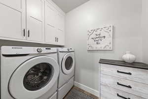 Laundry area featuring cabinet space, separate washer and dryer, and wood finished floors