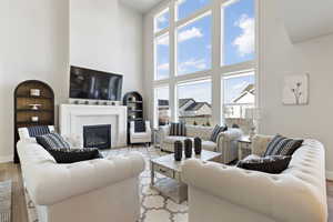 Living area with light wood-type flooring, built in features, a high ceiling, and a glass covered fireplace