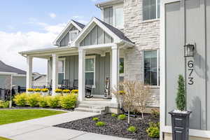 Entrance to property with board and batten siding, stone siding, and covered porch