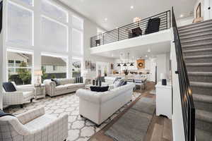 Living room featuring wood finished floors, recessed lighting, and a high ceiling
