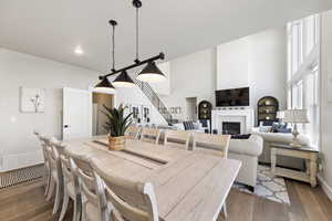 Dining area featuring wood finished floors, a glass covered fireplace, and a high ceiling