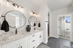 Full bathroom featuring double vanity and dark tile patterned floors