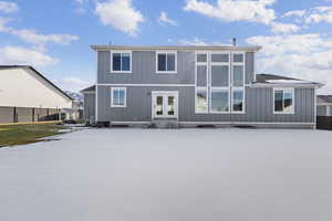 Snow covered house with french doors and board and batten siding
